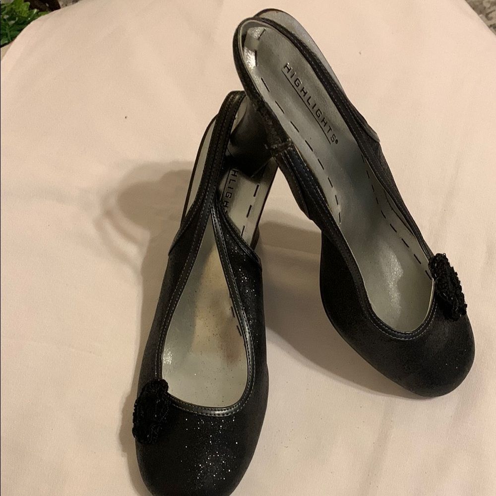 Highlights black block heels with crocheted flower on each shoe